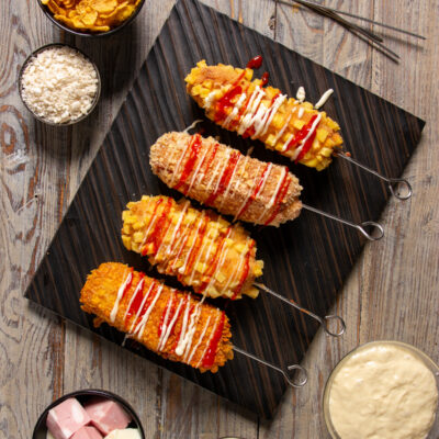Korean corn dog fritti su spiedino con panature diverse, ketchup e maionese a filo