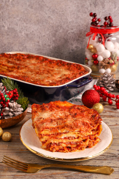 Lasagne delle Feste con strati di ragù e besciamella, servite a fetta con la teglia sullo sfondo