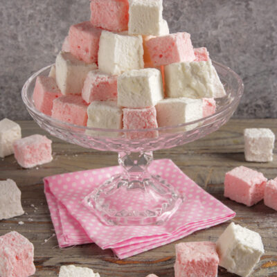 Marshmallow fatti in casa impilati a piramide, bianchi e rosa, con zucchero a velo