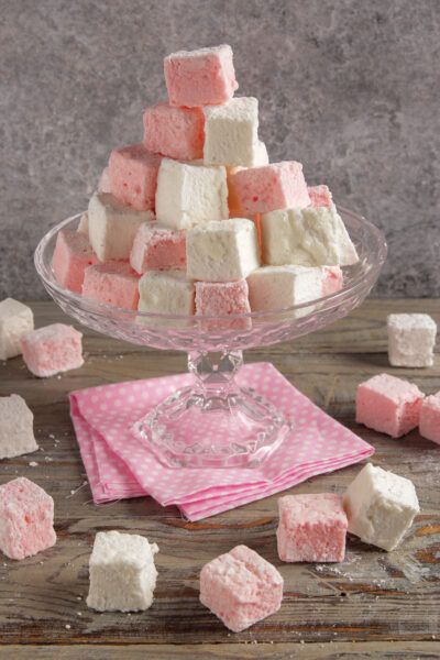 Marshmallow fatti in casa impilati a piramide, bianchi e rosa, con zucchero a velo
