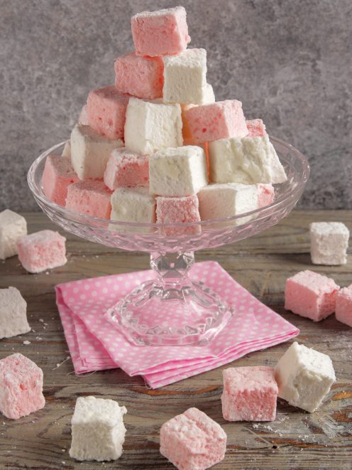Marshmallow fatti in casa impilati a piramide, bianchi e rosa, con zucchero a velo