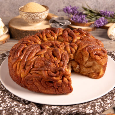 Cinnamon tangle cake intrecciata e caramellata, servita intera con una fetta staccata sul piatto