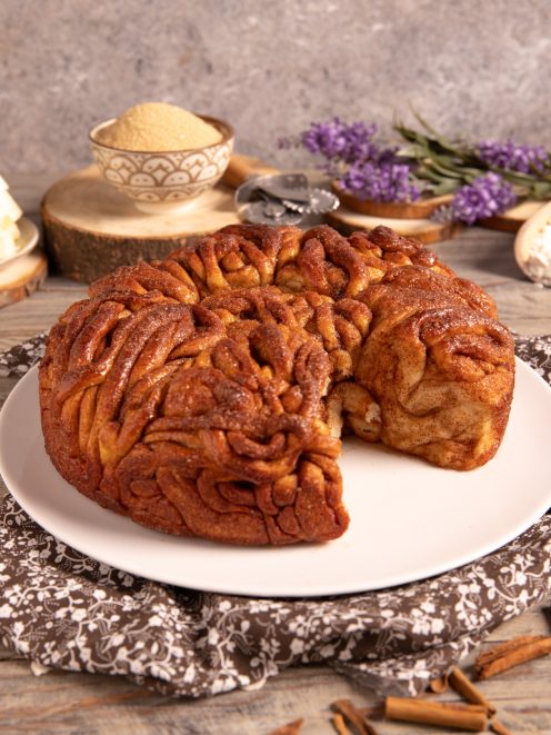 Cinnamon tangle cake intrecciata e caramellata, servita intera con una fetta staccata sul piatto