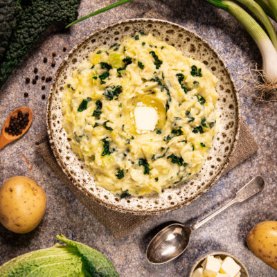 Colcannon con purè di patate e cavolo nero servito in ciotola con una noce di burro fuso al centro
