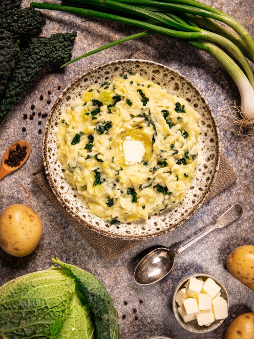 Colcannon con purè di patate e cavolo nero servito in ciotola con una noce di burro fuso al centro