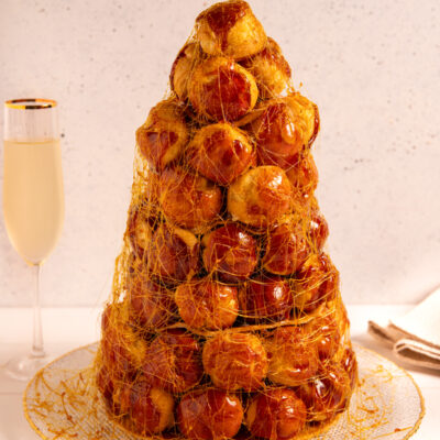 Croquembouche a torre di bignè caramellati avvolti in un velo di zucchero filato dorato