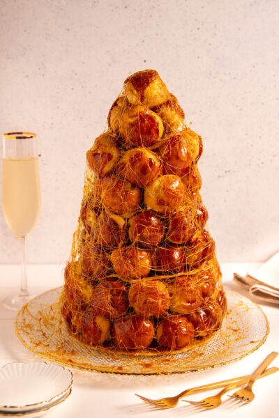 Croquembouche a torre di bignè caramellati avvolti in un velo di zucchero filato dorato