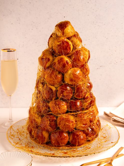 Croquembouche a torre di bignè caramellati avvolti in un velo di zucchero filato dorato