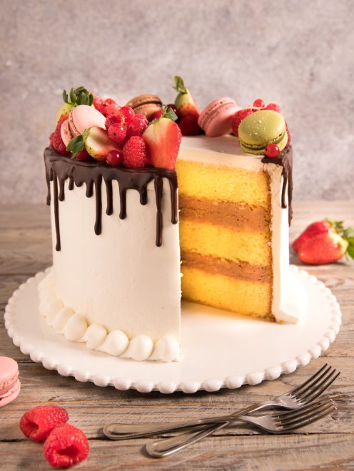 Drip cake con strati di pan di spagna e crema, glassa al cioccolato e frutti di bosco freschi
