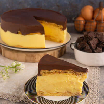 Torta eclair a fette con strati di crema pasticcera, pasta sfoglia e copertura di ganache al cioccolato
