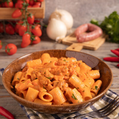 Pasta alla carcerata con rigatoni conditi da sugo cremoso di salsiccia e pomodoro, guarniti con prezzemolo