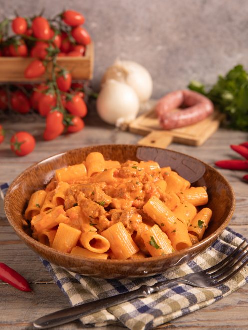 Pasta alla carcerata con rigatoni conditi da sugo cremoso di salsiccia e pomodoro, guarniti con prezzemolo