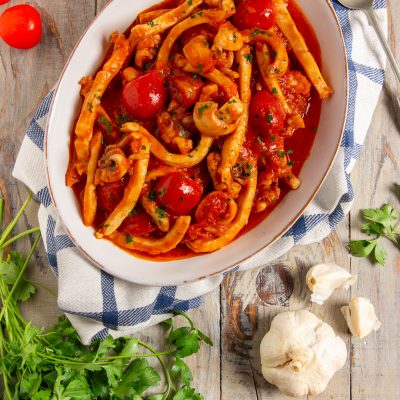 Seppie in umido con pomodorini interi e sugo rosso, guarnite con prezzemolo tritato