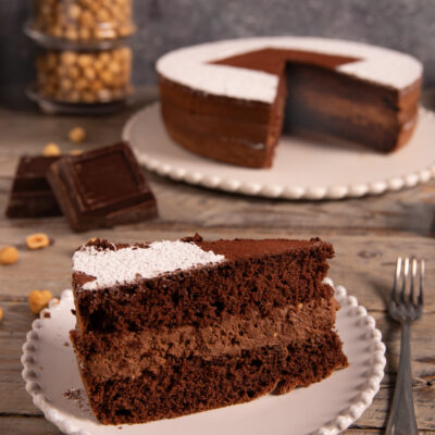 Torta cioccolato e nocciole in sezione, con strato di crema e zucchero a velo sulla superficie