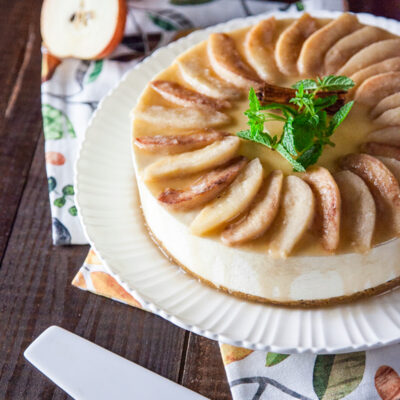 Cheesecake senza glutine con spicchi di pere caramellate disposti a raggiera e stecca di cannella al centro