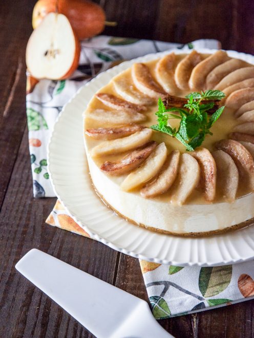 Cheesecake senza glutine con spicchi di pere caramellate disposti a raggiera e stecca di cannella al centro