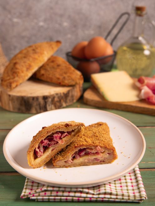 Panzerotti di carne fritti e impanati, tagliati a metà con ripieno di formaggio filante e crudo