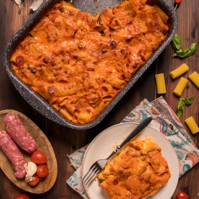 Pasta cremosa al forno con salsiccia, gratinata con salsa di pomodoro, servita in teglia e nel piatto
