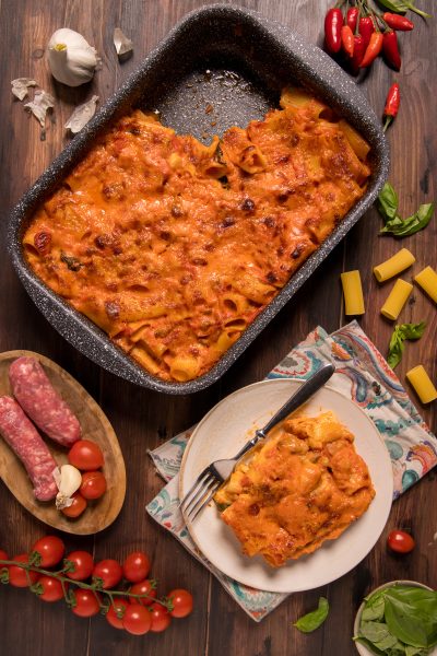 Pasta cremosa al forno con salsiccia, gratinata con salsa di pomodoro, servita in teglia e nel piatto