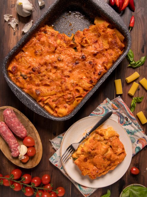 Pasta cremosa al forno con salsiccia, gratinata con salsa di pomodoro, servita in teglia e nel piatto