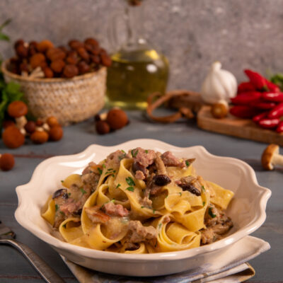 Pasta con funghi e salsiccia condita con prezzemolo fresco in salsa cremosa