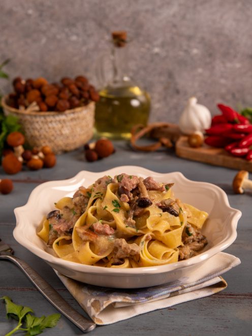 Pasta con funghi e salsiccia condita con prezzemolo fresco in salsa cremosa