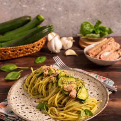 Pasta tonno e zucchine con crema verde, fettine di zucchina e pezzi di tonno, guarnita con foglie di basilico