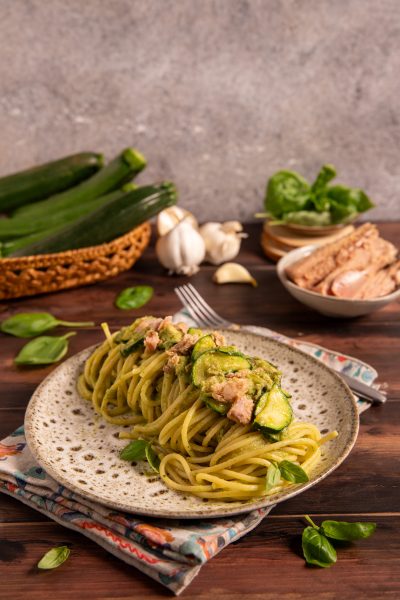 Pasta tonno e zucchine con crema verde, fettine di zucchina e pezzi di tonno, guarnita con foglie di basilico
