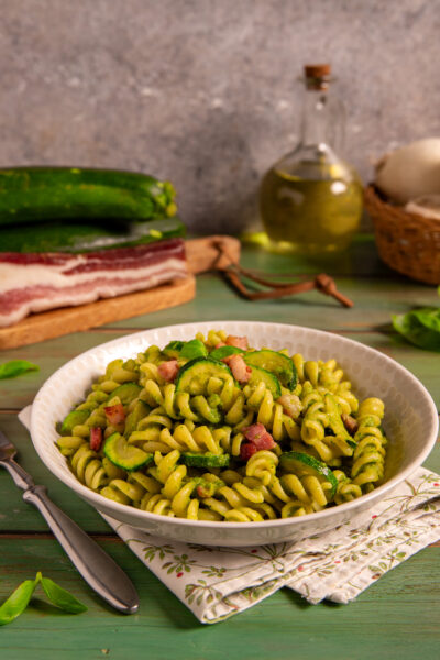 Pasta zucchine e pancetta con fusilli al pesto di zucchine, rondelle saltate e cubetti di pancetta