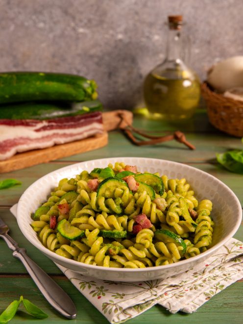 Pasta zucchine e pancetta con fusilli al pesto di zucchine, rondelle saltate e cubetti di pancetta
