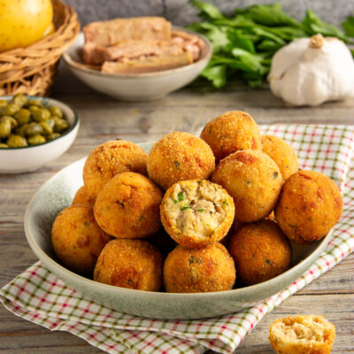 Polpette di tonno fritte dorate, una spezzata rivela il ripieno morbido con erbe
