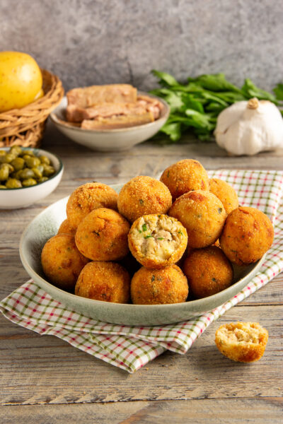 Polpette di tonno fritte dorate, una spezzata rivela il ripieno morbido con erbe
