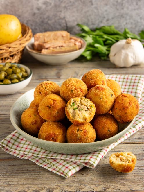 Polpette di tonno fritte dorate, una spezzata rivela il ripieno morbido con erbe