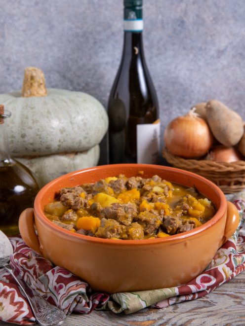 Spezzatino con patate e zucca servito in tegame di terracotta con sugo dorato