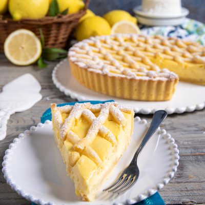 Fetta di crostata della babbaiola con crema al limone e copertura a treccia spolverata di zucchero a velo