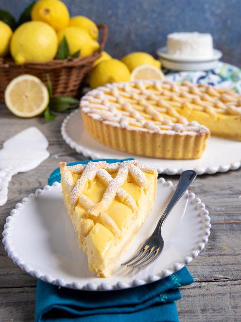 Fetta di crostata della babbaiola con crema al limone e copertura a treccia spolverata di zucchero a velo