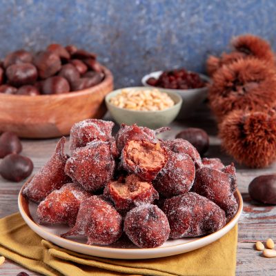 Frittelle di castagne fritte e zuccherate impilate nel piatto, una spezzata rivela il ripieno morbido