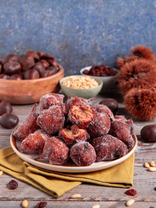 Frittelle di castagne fritte e zuccherate impilate nel piatto, una spezzata rivela il ripieno morbido