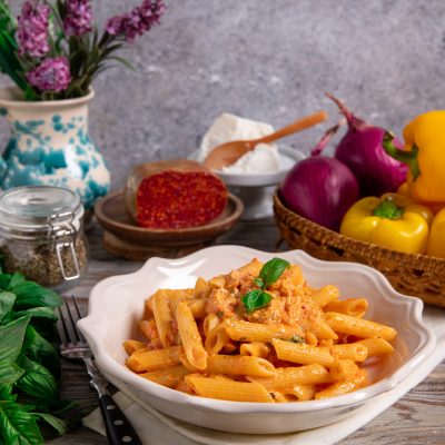 Pasta con pesto alla calabrese in penne cremose guarnite con foglie di basilico fresco