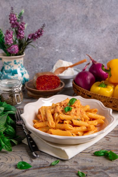 Pasta con pesto alla calabrese in penne cremose guarnite con foglie di basilico fresco