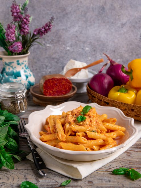 Pasta con pesto alla calabrese in penne cremose guarnite con foglie di basilico fresco