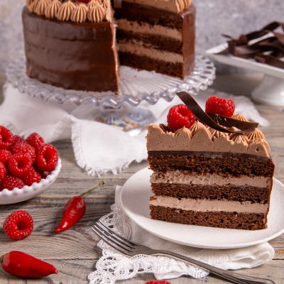 Torta al doppio cioccolato e peperoncino a strati, fetta con crema al cioccolato e lamponi