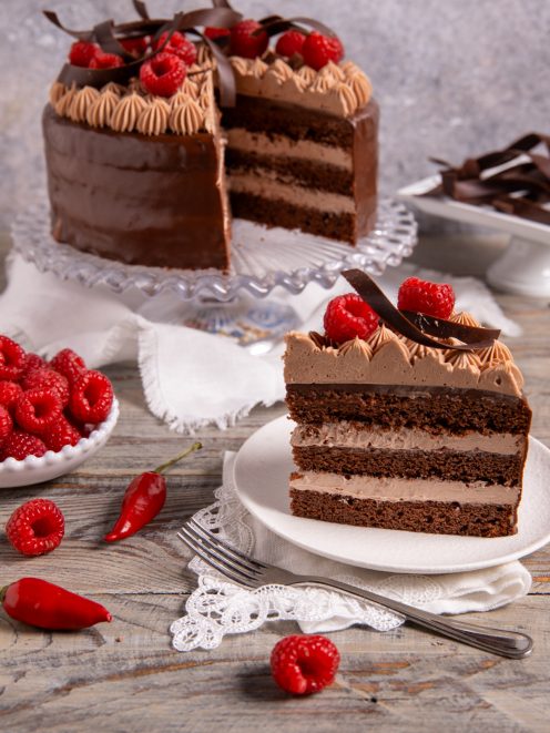 Torta al doppio cioccolato e peperoncino a strati, fetta con crema al cioccolato e lamponi
