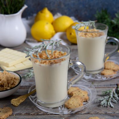 Cioccolata calda bianca in tazze di vetro con crumble al limone e rametti di rosmarino brinato