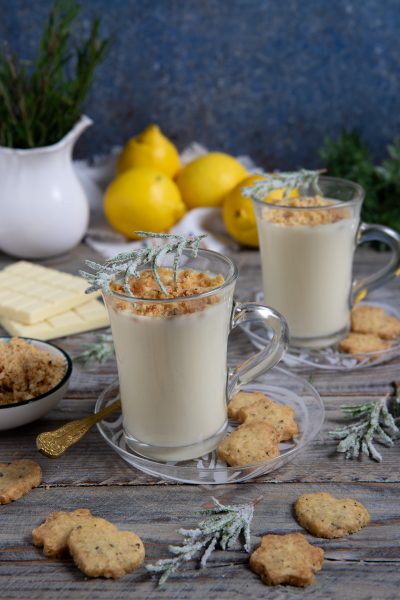 Cioccolata calda bianca in tazze di vetro con crumble al limone e rametti di rosmarino brinato