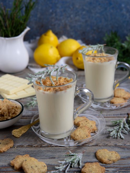 Cioccolata calda bianca in tazze di vetro con crumble al limone e rametti di rosmarino brinato