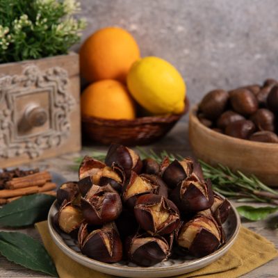 Castagne bollite con guscio aperto servite su un piatto, con rosmarino e foglie di alloro