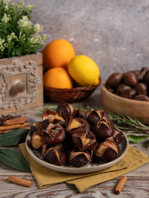 Castagne bollite con guscio aperto servite su un piatto, con rosmarino e foglie di alloro