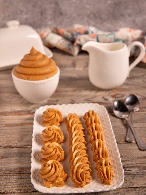 Ganache al caramello salato disposta in ciuffi e strisce decorative su vassoio traforato