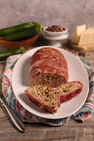 Rotolo di prosciutto di Federico Fellini affettato, con ripieno di carne e pistacchi in vista